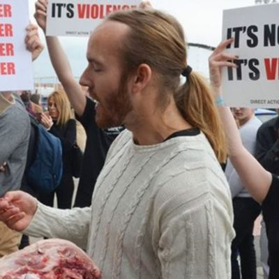 Hombre come cabeza de cerdo cruda frente a festival de vegetarianos